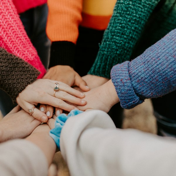 A group of people stacking their hands together in unity